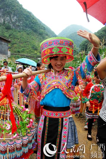 漂亮的瑶族姑娘挑着鸡蛋笼,热情大方地向游客打招呼(刘廷智/摄)